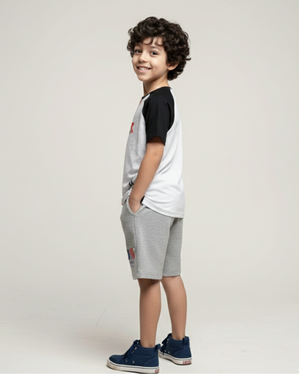Side View boy's wearing a black and white shirt with gray shorts on a plain background
