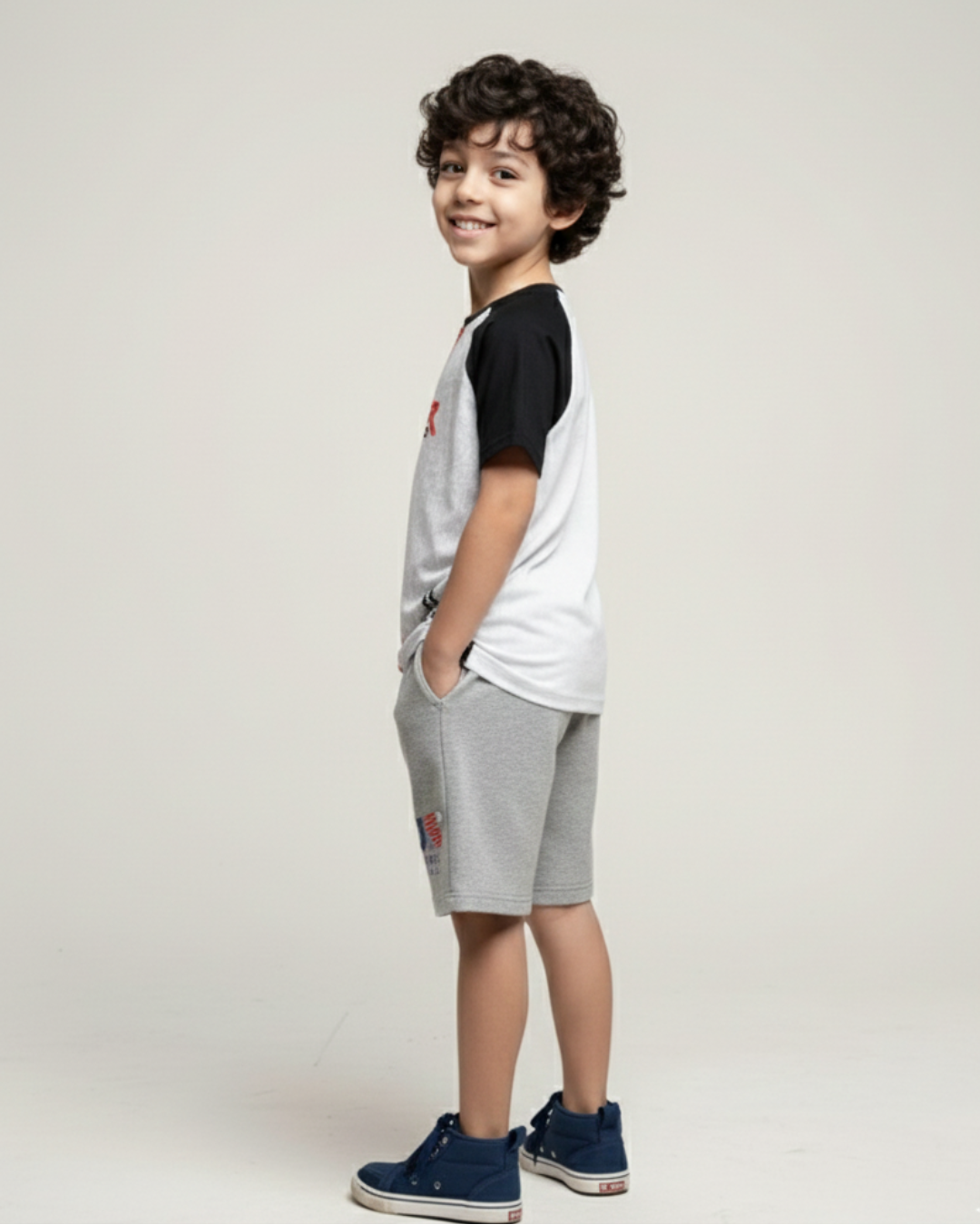 Side View boy's wearing a black and white shirt with gray shorts on a plain background