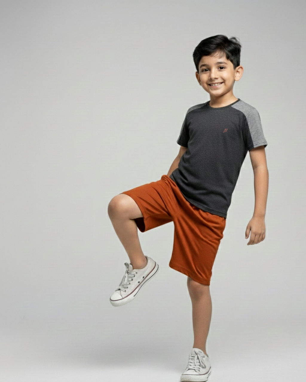Boy's wearing a gray and black t-shirt with orange shorts on a plain background