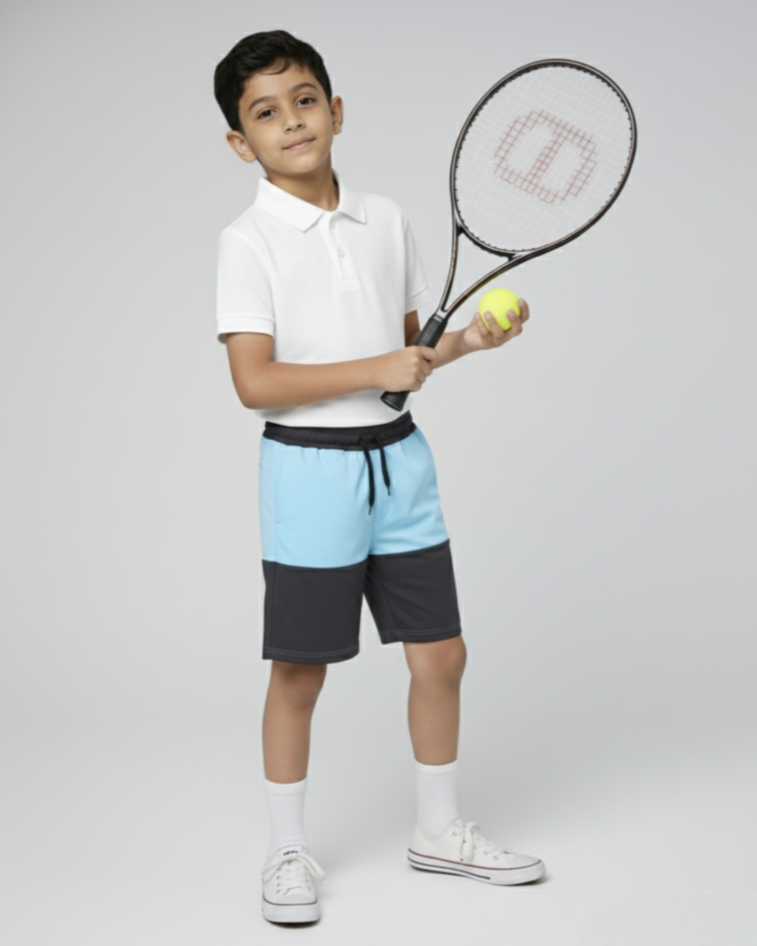 Child holding a tennis racket and ball on a plain background